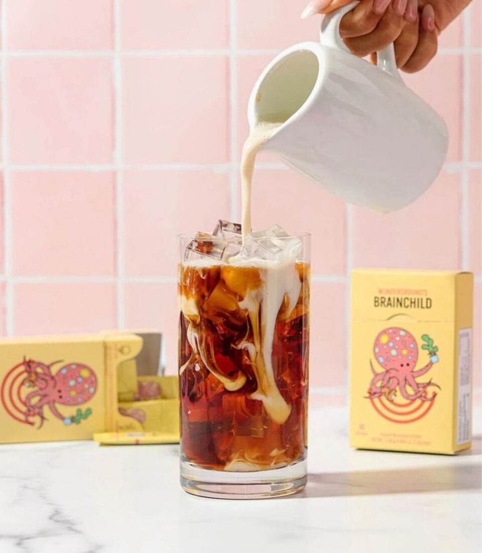 white mug pouring milk into an iced coffee