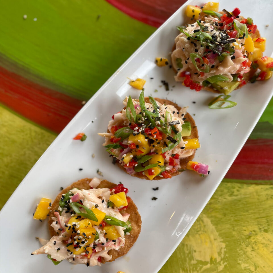 A long white plate with 3 crab tacos